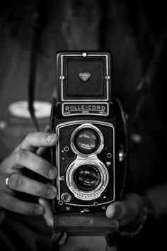 a person holding an old fashioned camera in their hands