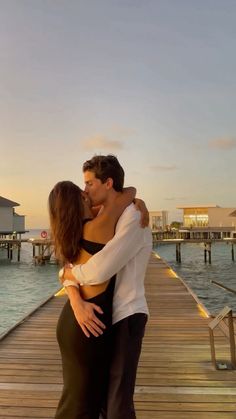 a man and woman kissing on a dock