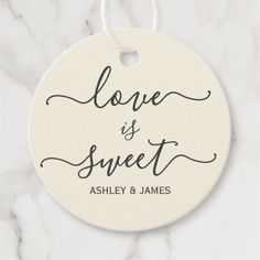 a white ceramic ornament with the words love is sweet on it, hanging from a marble background