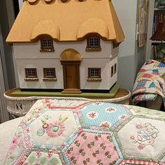 a doll house sitting on top of a table next to a stuffed animal and pillow