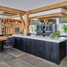 an open kitchen and dining room area with wood beams on the ceiling, black leather chairs