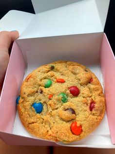 a cookie with m & m's in it sitting inside of a pink box