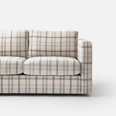 a white and brown plaid couch with pillows on it's back end, against a gray background