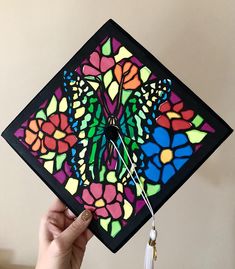 a hand holding a colorful square kite that has been made to look like a butterfly