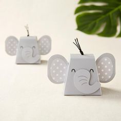 an elephant shaped ornament sitting on top of a white table next to a potted plant