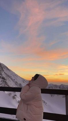 a person sitting on top of a bench in the snow with their back to the camera