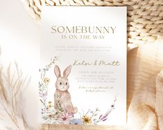 the bunny is on the way baby shower card with flowers and leaves in front of it