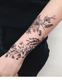 a woman's arm with flowers and leaves tattooed on the left side of her arm