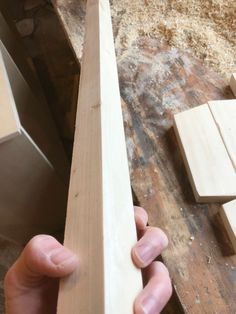 a person holding a piece of wood in their hand next to some pieces of wood