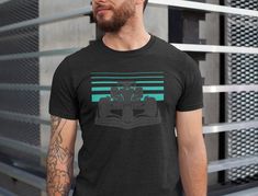 Perfect soft comfortable shirt for any Formula 1 fan! Featuring the colors of Mercedes AMG racing team, show off your support for  the team. The tri-blend fabric creates a vintage, fitted look. And extreme durability makes this t-shirt withstand repeated washings and still remain super comfortable. This t-shirt is everything you've dreamed of and more. It feels soft and lightweight, with the right amount of stretch. It's comfortable and flattering for all. * Softest cotton shirt you've ever felt thanks to special tri-blend finish * 50% polyester, 25% combed ring-spun cotton, 25% rayon * Fabric weight: 3.4 oz/yd² (115.3 g/m²) * Pre-shrunk for extra durability * Regular fit * Side-seamed construction Black Racing Fan Merchandise T-shirt, Black Tri-blend T-shirt For Sports Events, Black Graphic Print Tops For Motorsport Events, Mercedes Amg F1, Course Automobile, F1 Racing, Racing Team, Look Vintage, Star Shirt