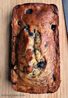 a loaf of blueberry bread sitting on top of a cutting board next to a knife