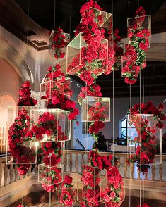 red flowers hanging from the ceiling in a room with chandelier and staircases