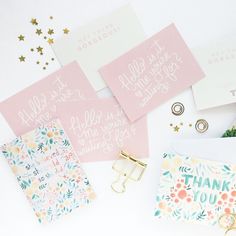 pink and gold stationery with thank you notes on them next to other stationery items