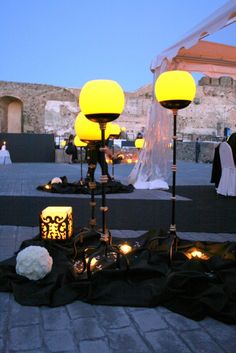 a couple of lamps sitting on top of a stone floor next to each other in front of a building