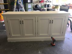 a white cabinet in a garage with tools on the floor