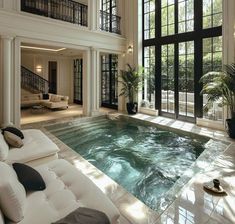 an indoor swimming pool in the middle of a large living room with lots of windows