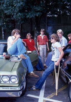 a group of people standing around a car in a parking lot