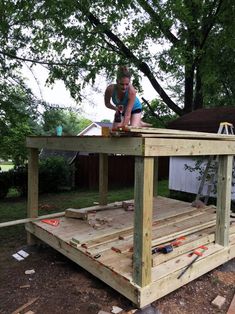 a woman working on a wooden structure in the yard