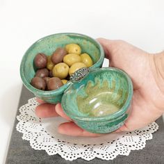 a hand holding two bowls filled with olives