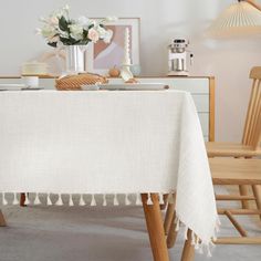 a white table cloth with tassels is on a wooden chair in front of a dresser