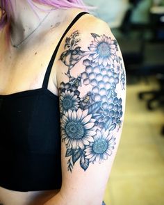 a woman with pink hair wearing a black bra top and flowers on her left arm