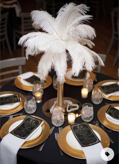 there is a table set with gold and white plates, silverware, and a palm tree centerpiece