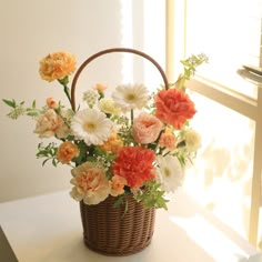 a basket filled with lots of flowers on top of a white table next to a window