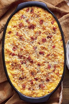 a casserole dish with cheese and bacon in it on a table next to a plate