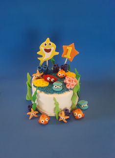 a birthday cake decorated with fondant fish and under the sea themed decorations on a blue background