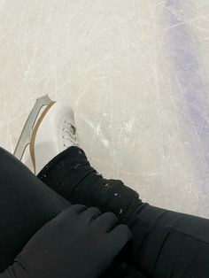 someone is sitting on the ice with their feet in the air and wearing black gloves