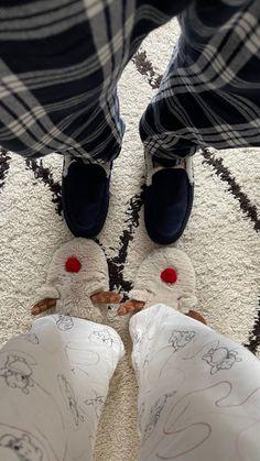 two people wearing slippers standing in front of a rug