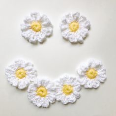 three crocheted flowers arranged in the shape of a circle on a white surface