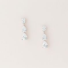 three pear shaped diamond earrings on a white background