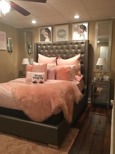 a bed with pink pillows and blankets in a room that is well lit by the ceiling fan