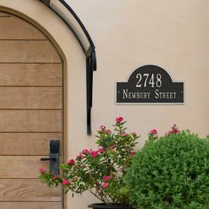 there is a potted plant with pink flowers in front of the address sign for newbury street