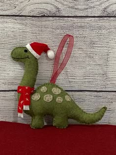 a stuffed toy dinosaur with a santa hat and scarf on it's back sitting against a wooden wall