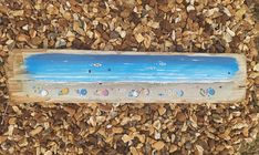 a wooden sign sitting on top of a pile of wood next to a beach and ocean