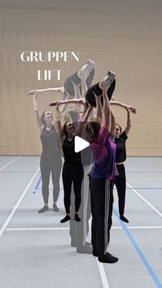 a group of people standing on top of a tennis court holding up their hands in the air