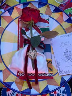 a red rose sitting on top of a plate next to a note and napkins