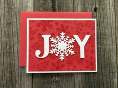 a red card with white snowflakes on it and the word joy written in large letters