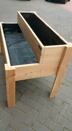 a wooden bed frame sitting on top of a brick floor next to a parking lot