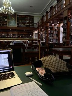 an open laptop computer sitting on top of a desk next to a book shelf filled with books