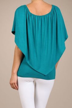 the back view of a woman wearing white pants and a teal top with an open neck