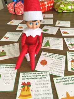 an elf is sitting on the table surrounded by christmas cards