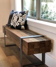 a wooden bench with a black and white pillow on it next to a window sill