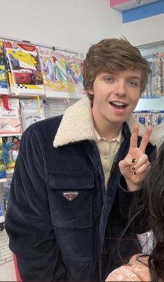 a man standing next to a woman in a store giving the peace sign with her fingers