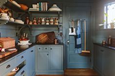 a kitchen with blue cupboards and shelves filled with cooking utensils, pots and pans