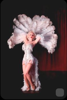 the woman is dressed in white feathers and posing