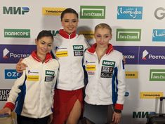 three young women standing next to each other in front of a wall