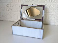 an empty silver box sitting on top of a white table next to a brick wall